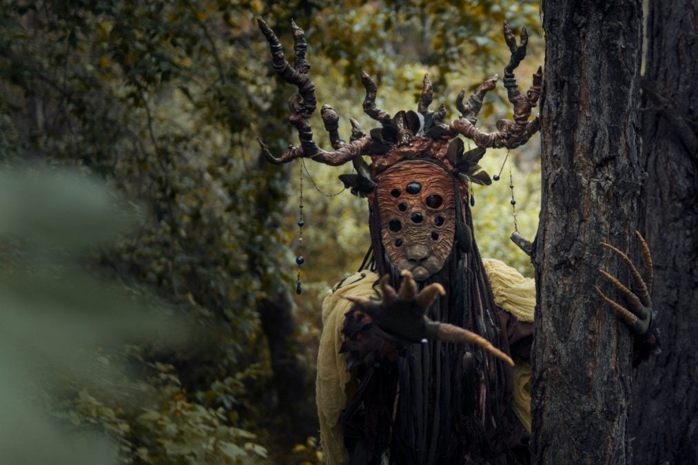 Une personne avec un masque et des cornes dans les bois