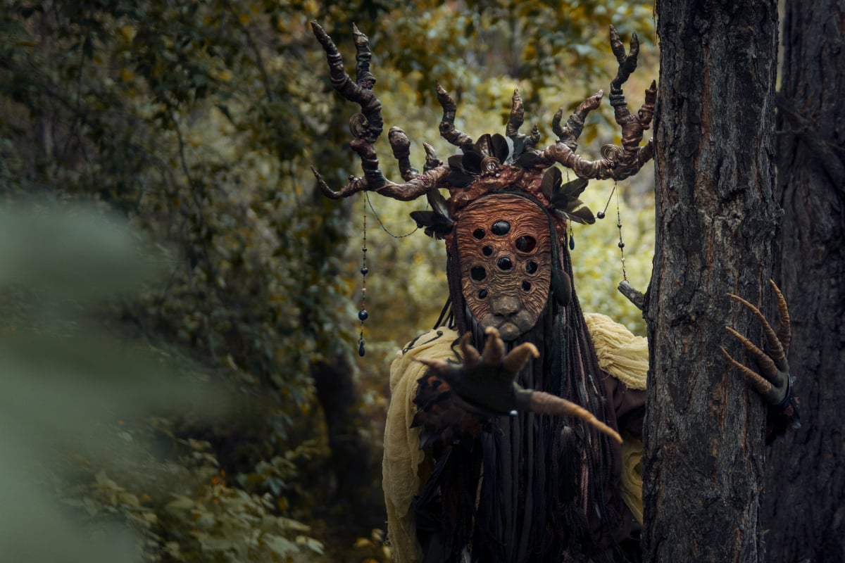 Une personne avec un masque et des cornes dans les bois